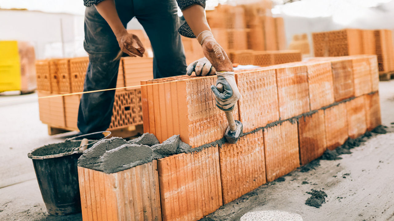 Ein Handwerker mauert eine Ziegelwand