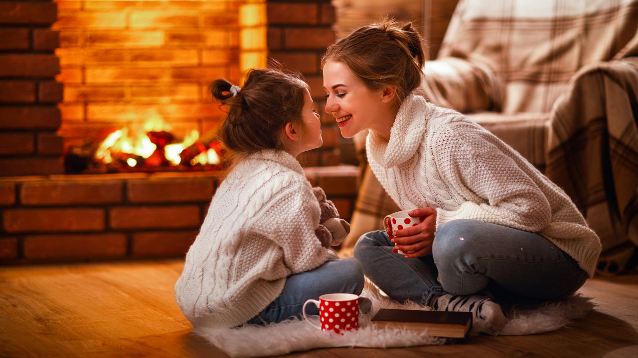 Eine Mutter mit ihrer Tochter vor einem offenen Kaminfeuer