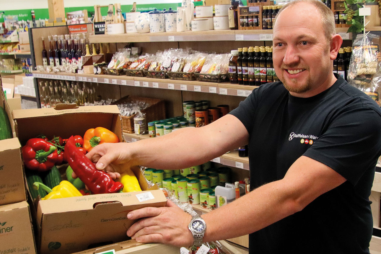 Ein Mitarbeiter im Raiffeisenmarkt präsentiert eine Gemüsekiste