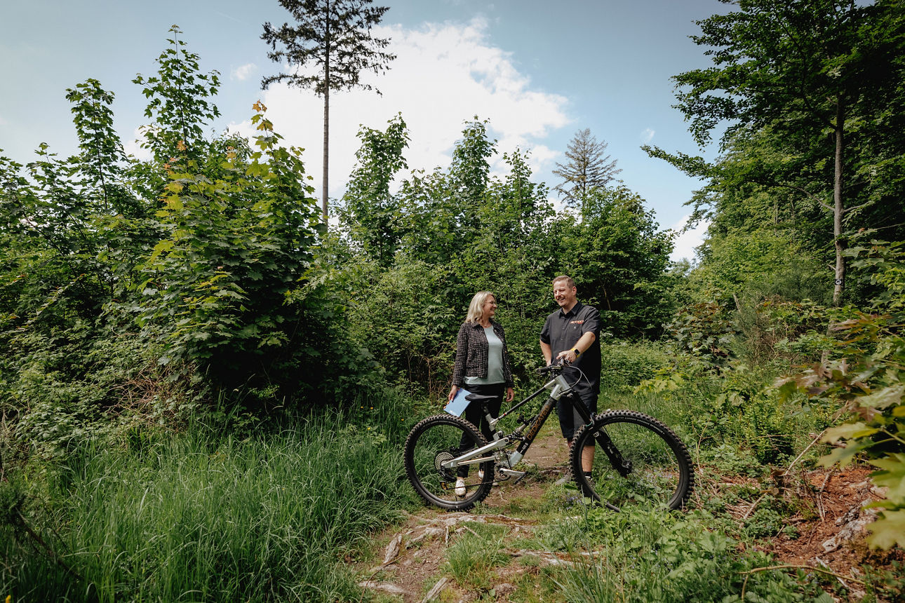 Volksbank in Südwestfalen Beraterin mit Startup-Kunden am Biketrail im Wald