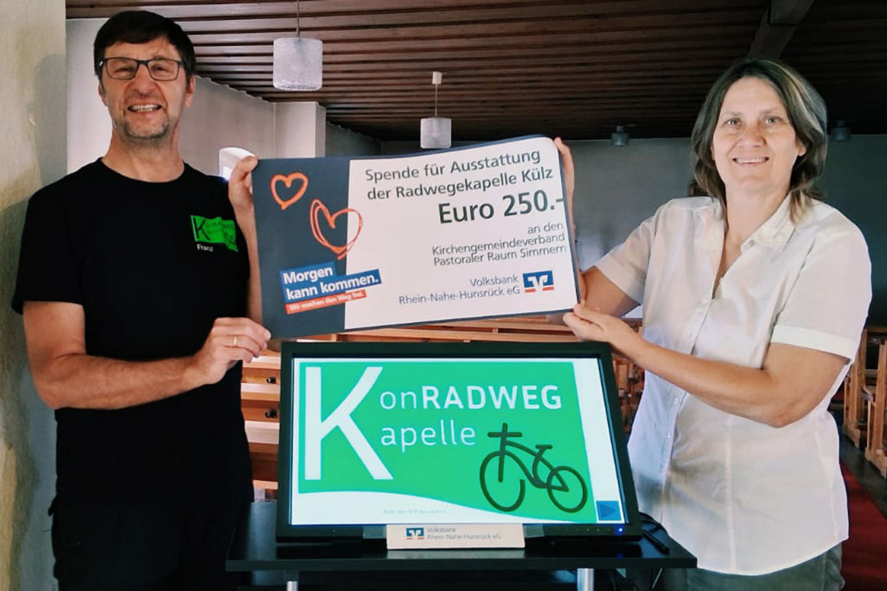 Erwachsene halten einen Spendenscheck in der Hand.