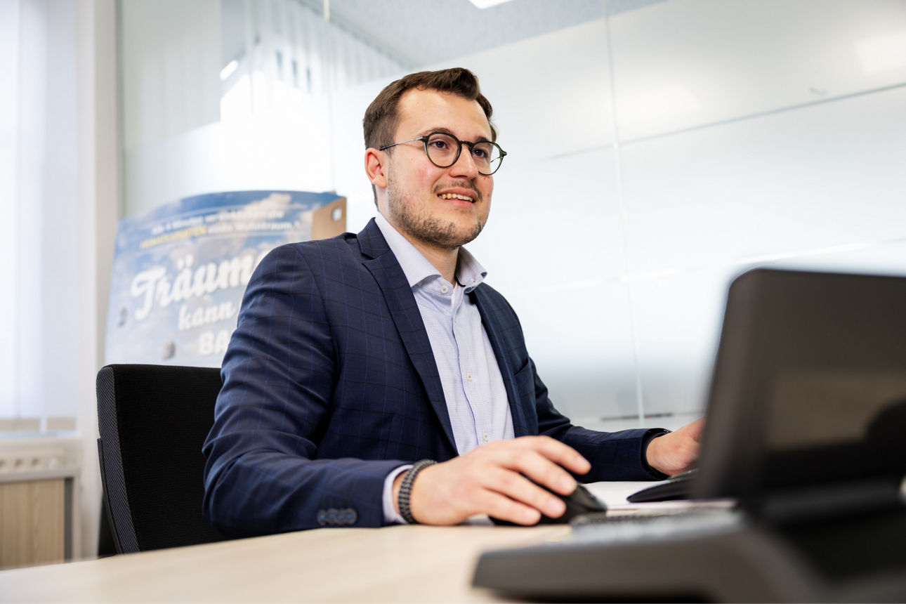 Mann arbeitet an einem Schreibtisch und blickt auf den Monitor