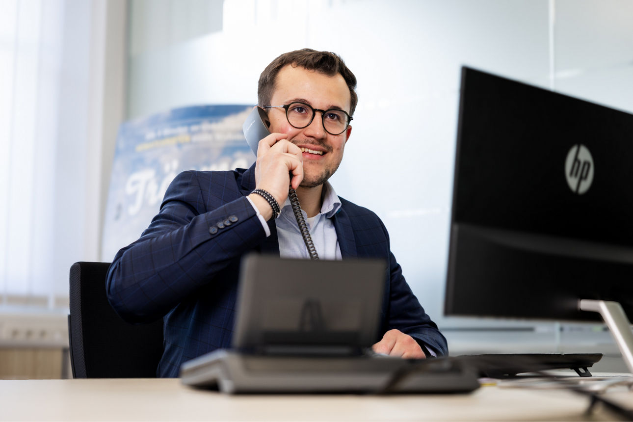 Mann sitzt an einem Schreibtisch und telefoniert