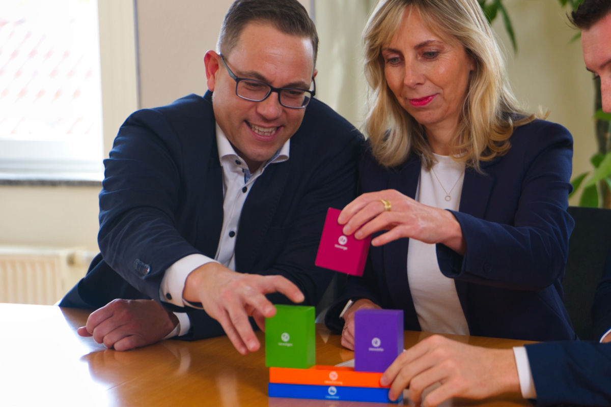 Mitarbeitende setzen Hausbankbausteine übereinander