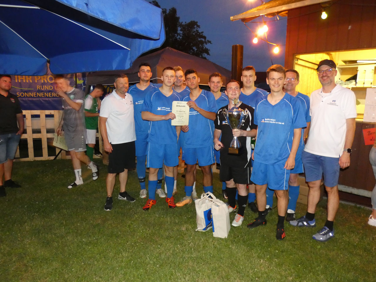 Gewinnerteam steht mit Urkunde und Pokal auf dem Rasen