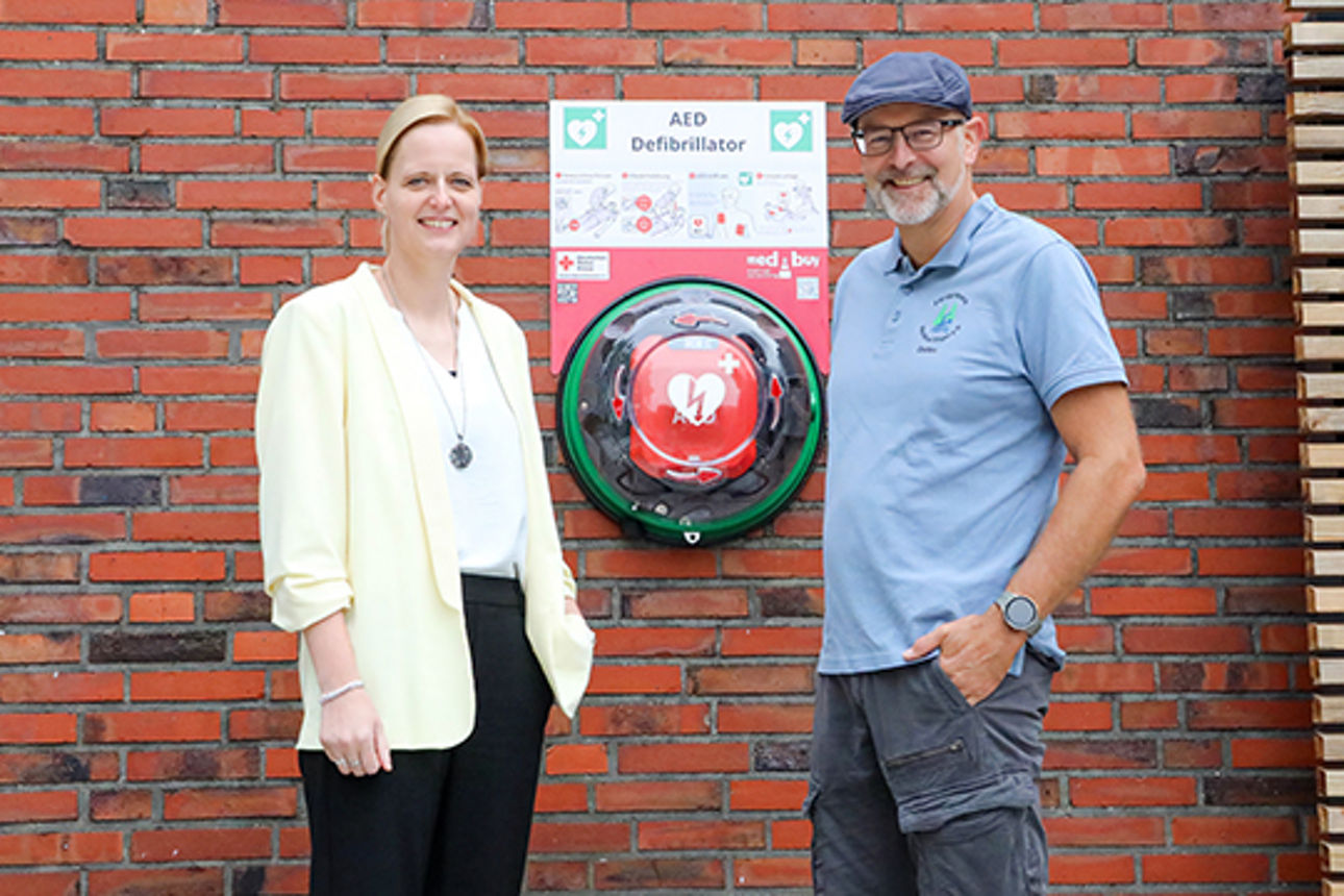 Ein Mann und eine Frau neben dem Defibrillator in Waldbad Sögel