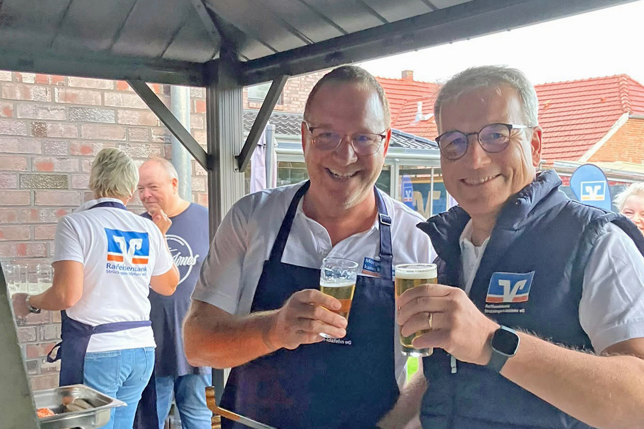 Raibamitarbeiter stehend am Grill mit einem Bier in der Hand