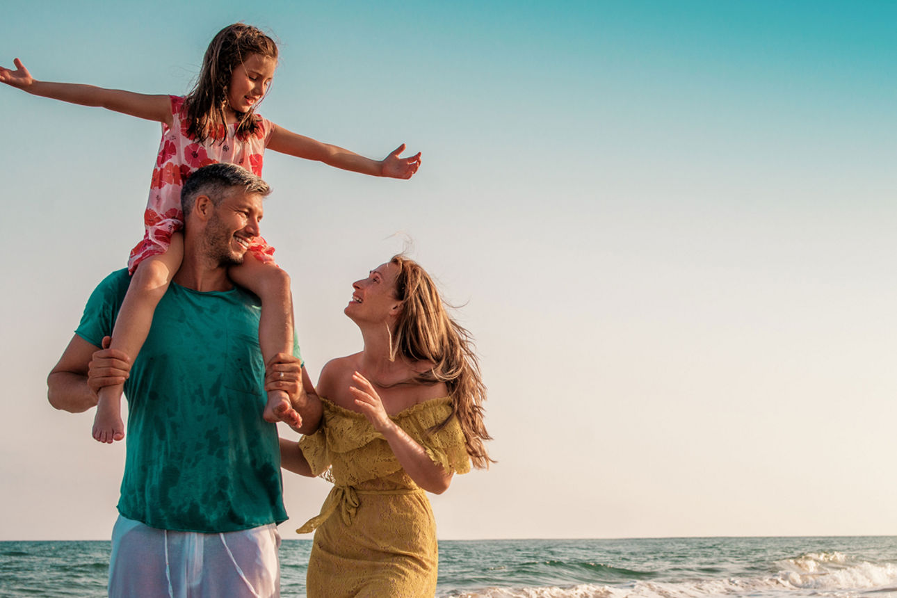 Mann, Frau und Tochter am Strand in der Sonne
