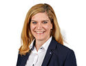 Ansprechpartnerin Daniela Rauh in einem Business Outfit lächelt in die Kamera