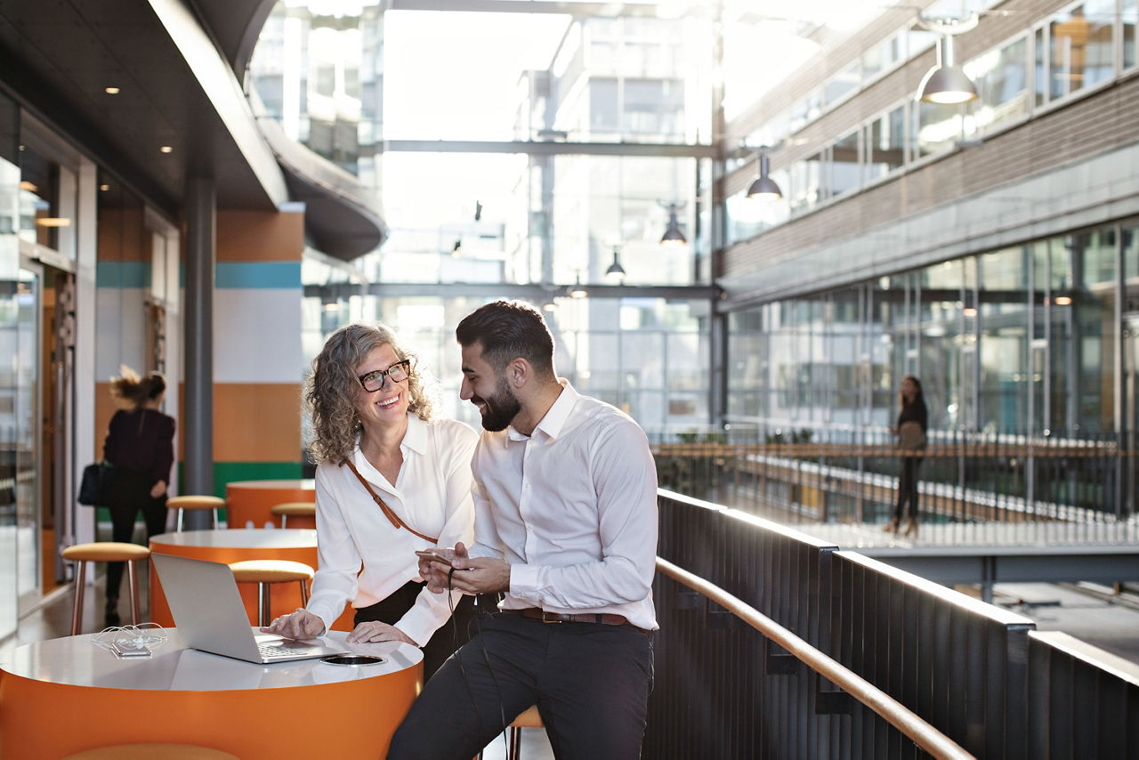 Frau und Mann stehen am Stehtisch mit Laptop