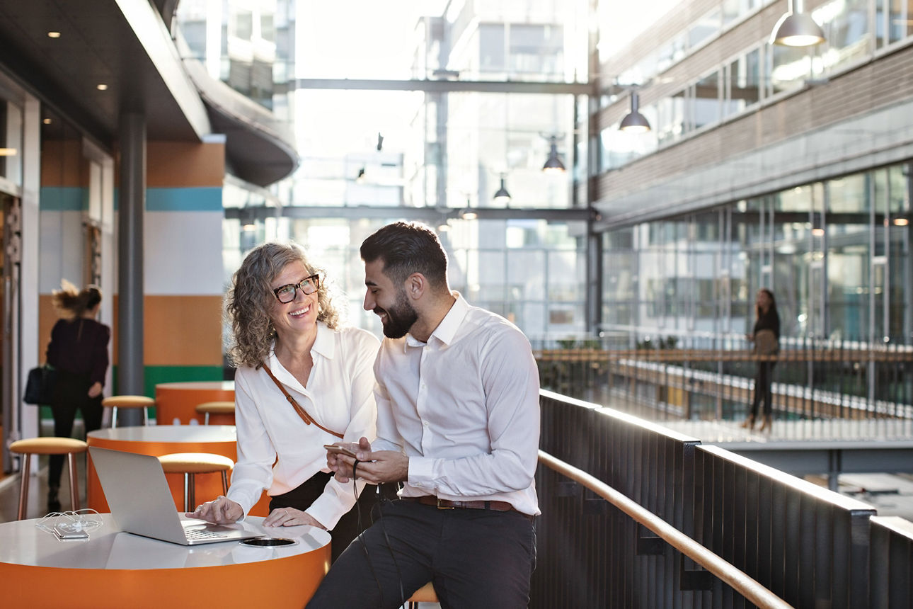 Frau und Mann stehen am Stehtisch mit Laptop