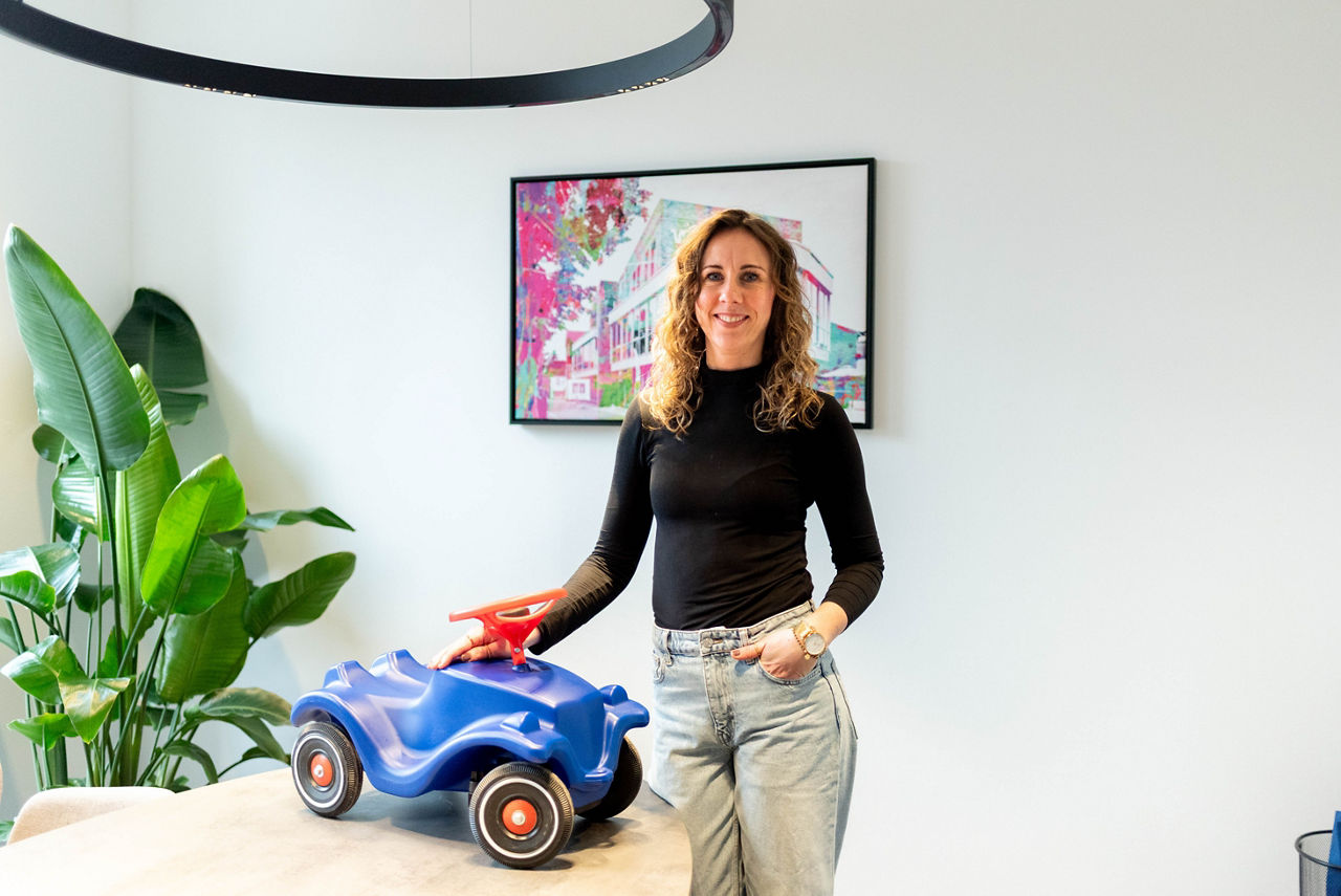 Natalie Neugebauer steht in einem Beratungsbüro mit einem Bobbycar auf dem Tisch.