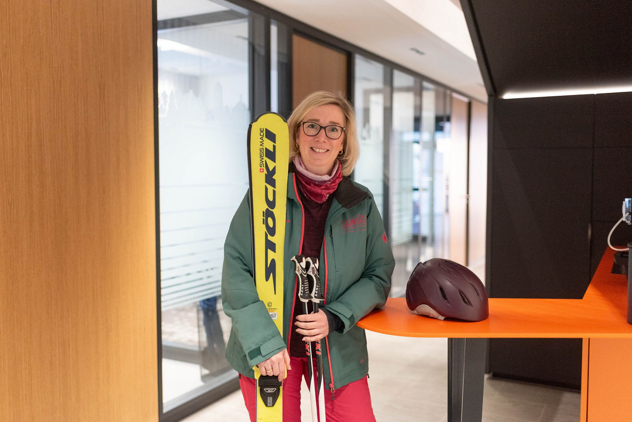 Uta Kleimann steht mit ihrer Skiausrüstung in unserer Bank an einem Stehtisch.