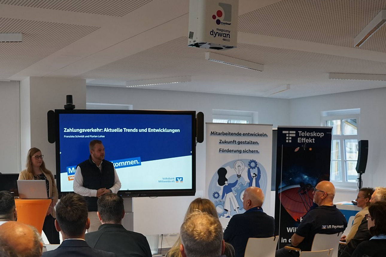 Business Frühstück 2.0: Blick in den Veranstaltungsraum von hinten, Besucher:innen sitzen und blicken zum Referenten