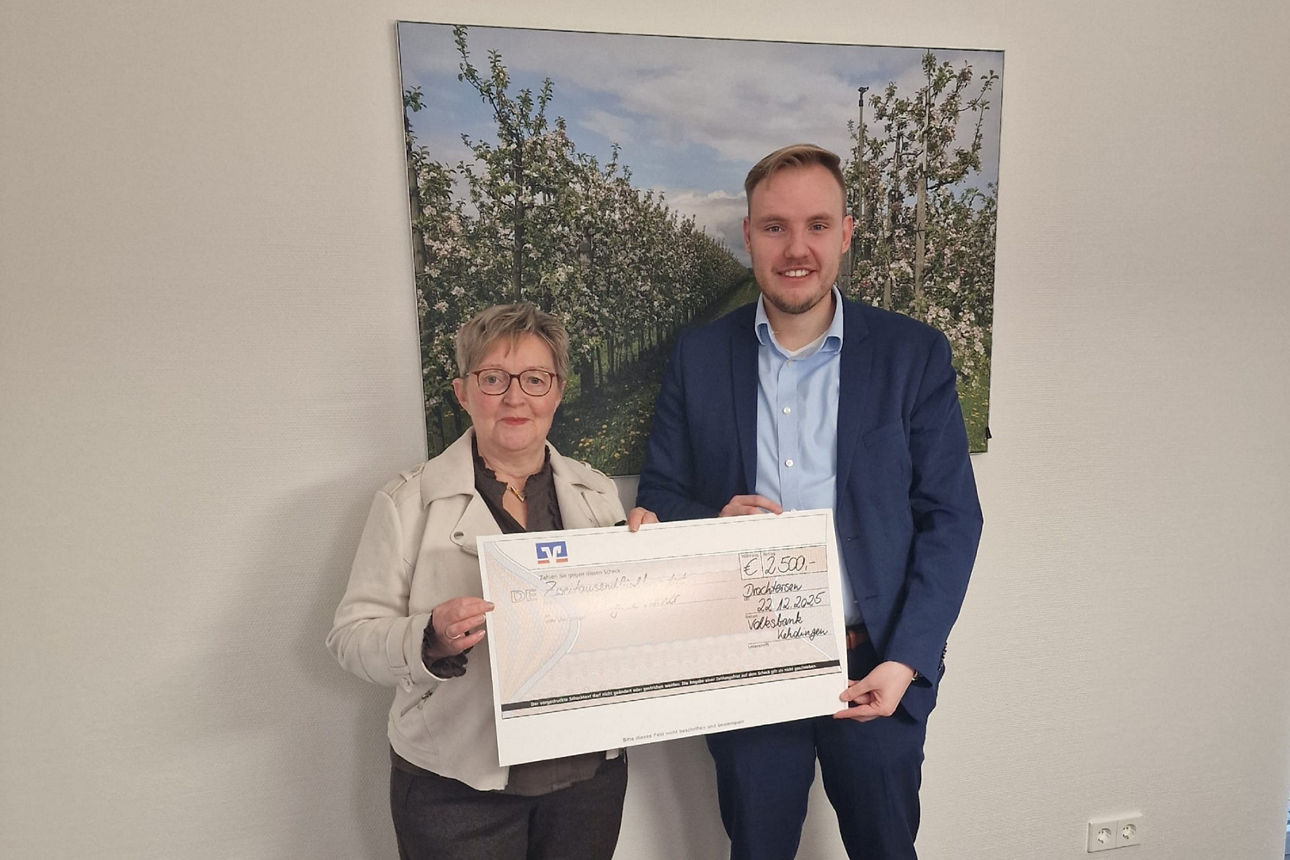 Regina Körner erhält den Reisegutschein von ihrem Kundenberater Jannis Krause