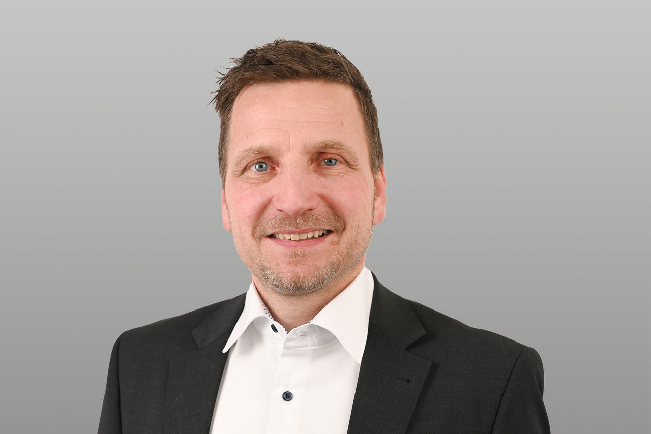 Privatkundenberater Adam Reicherl vor grauen Hintergrund