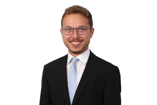 Freundlich lächelnder Mann im Anzug, unser Leiter KundenDialogCenter Niclas Reichmann