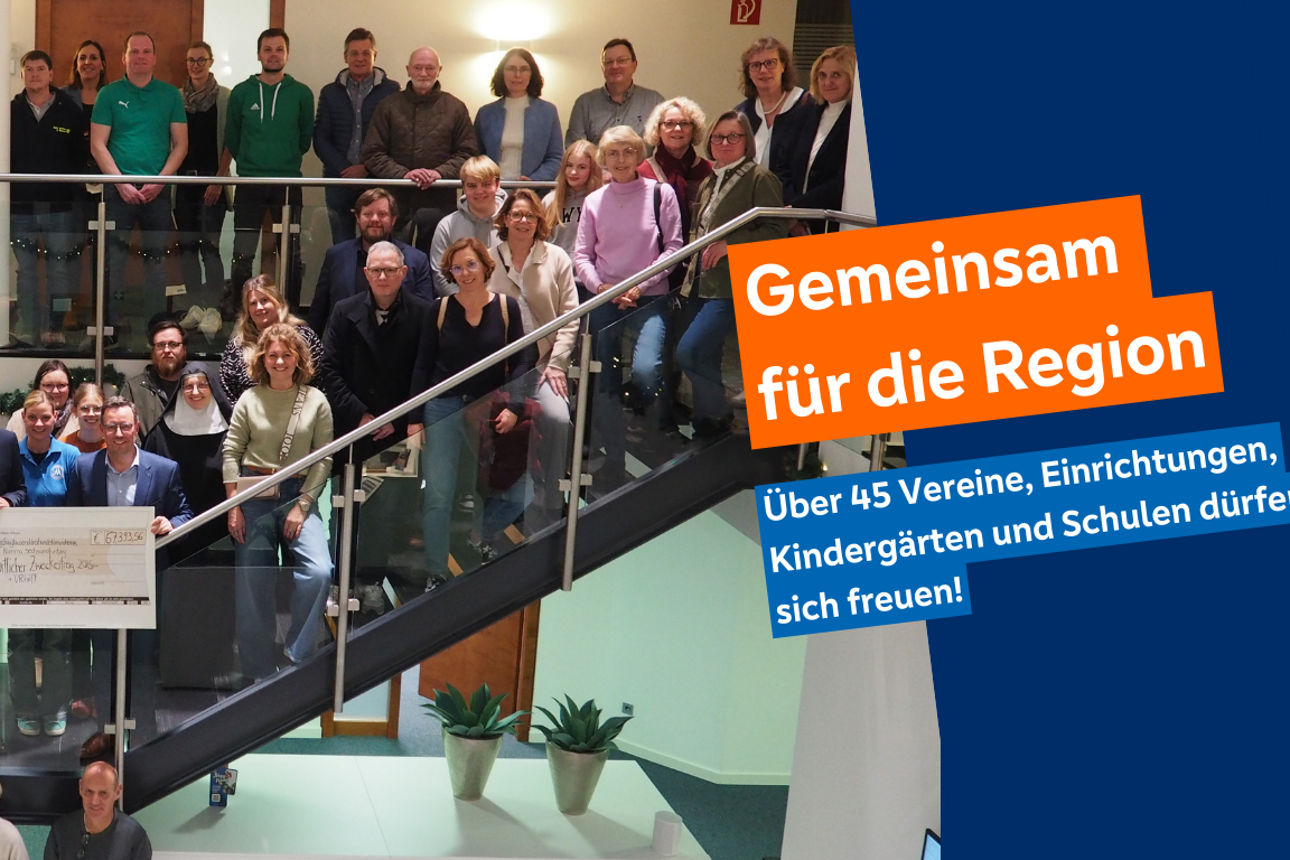 Eine große Gruppe steht um die Vorstände der Bank. Sie halten einen Scheck hoch.