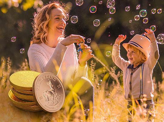 Mutter mit Tochter machen Seifenblasen auf einer Wiese. Zusätzlich sind Goldmünzen zu sehen
