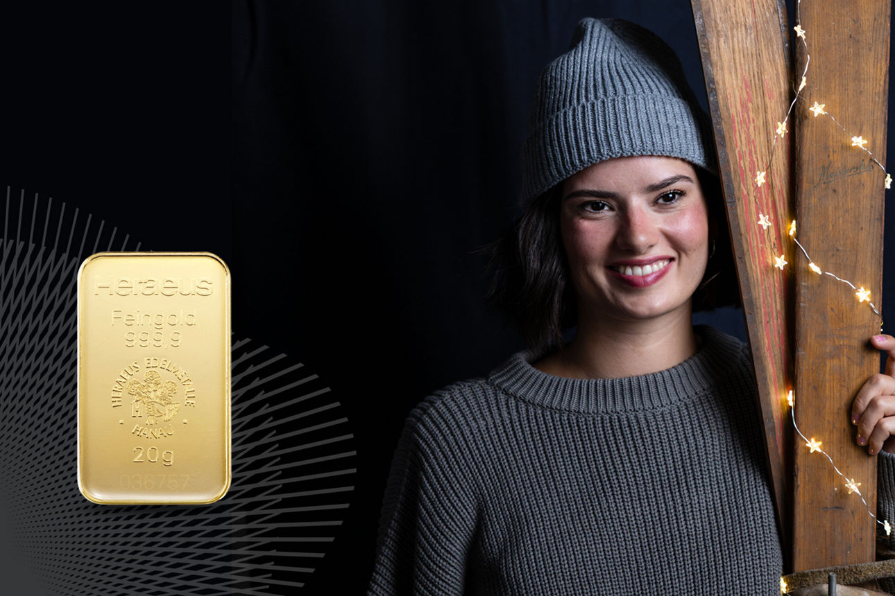 Lachenede Frau mit grauer Mütze auf dem Kopf und Goldbarren