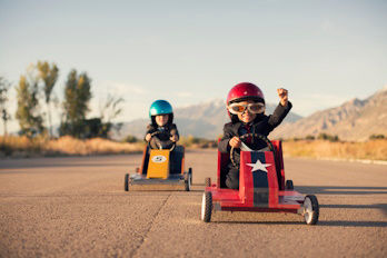 Zwei Kinder fahren in Kinder-Rennwagen