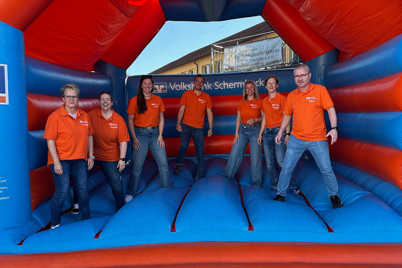 Teamfoto Rent a Banker auf orangener Volksbank-Hüpfburg