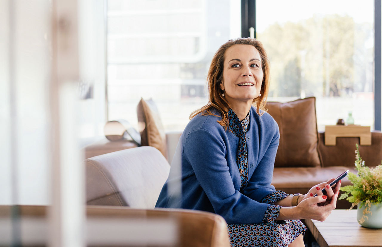 Eine Frau sitzt auf dem Sofa und hat ihr Handy in der Hand