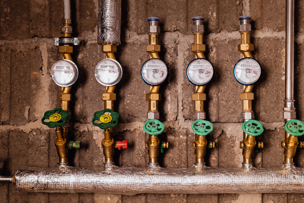 Reihe von Wasserzählern und Absperrventilen an einer Verteilereinheit im Bereich der Sanitär‑ und Haustechnikinstallation des Unternehmens „Ress GmbH“, eingebaut zur Steuerung und Überwachung der Wasserverteilung