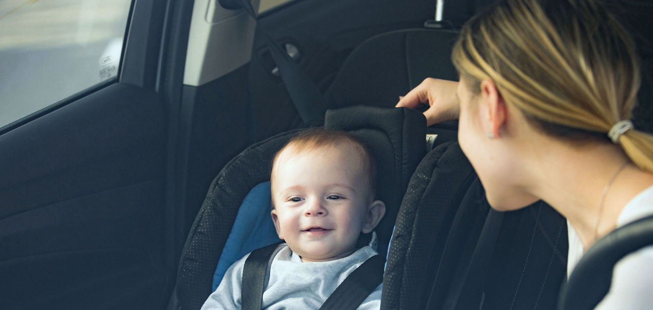 Eine Frau schaut ein Baby an, das sich im Kindersitz eines Autos  befindet