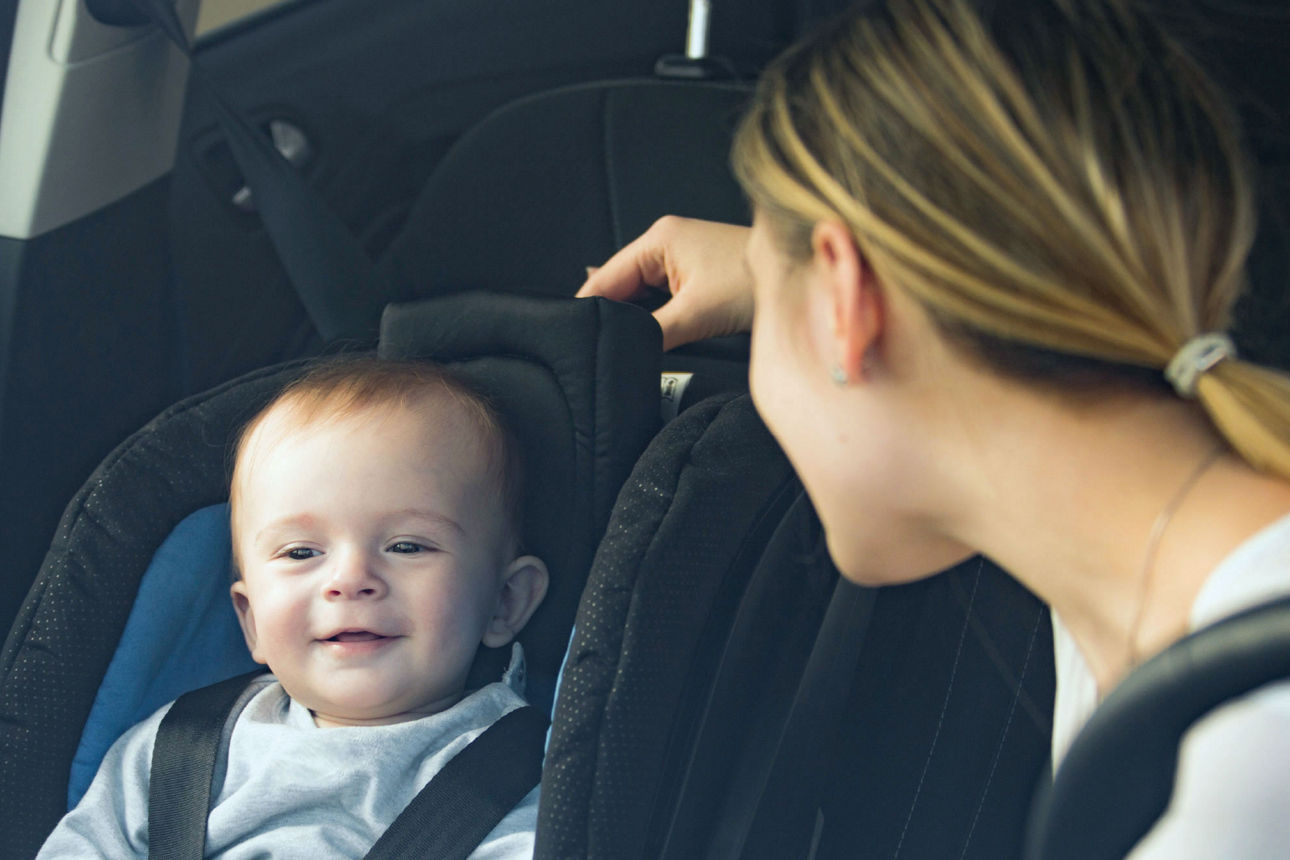 Eine Frau schaut ein Baby an, das sich im Kindersitz eines Autos  befindet