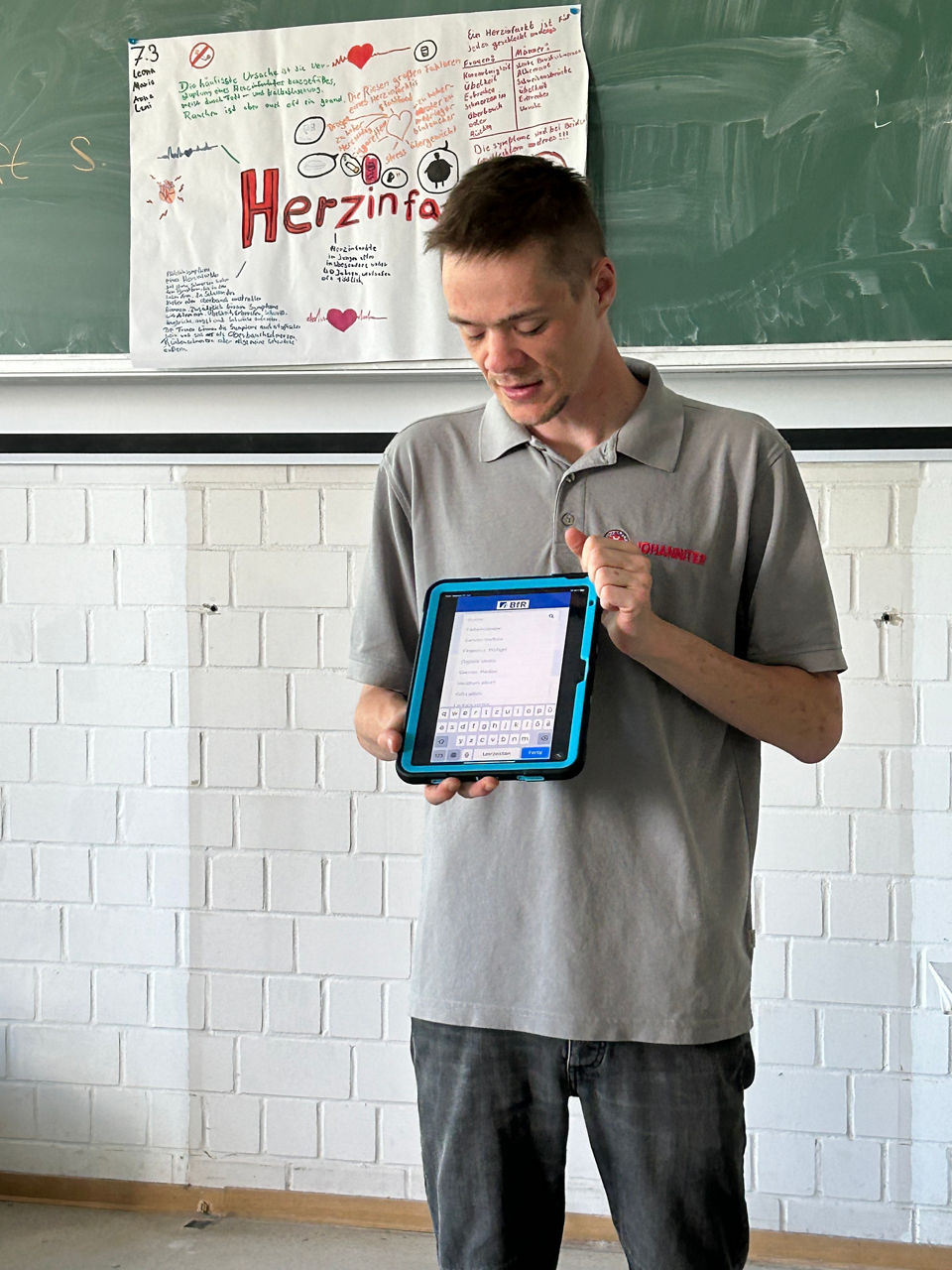 Junger Mann zeigt auf einem Tablet, passende Inahlte zum Thema "Retten macht Schule"