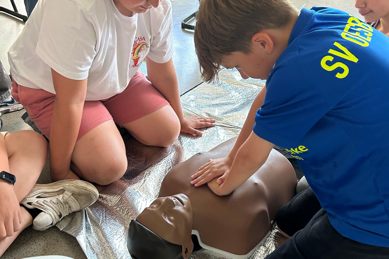 Kinder üben an einer Reanimationspuppe die Herzdruckmassage, um die Wiederbelebung zu lernen.