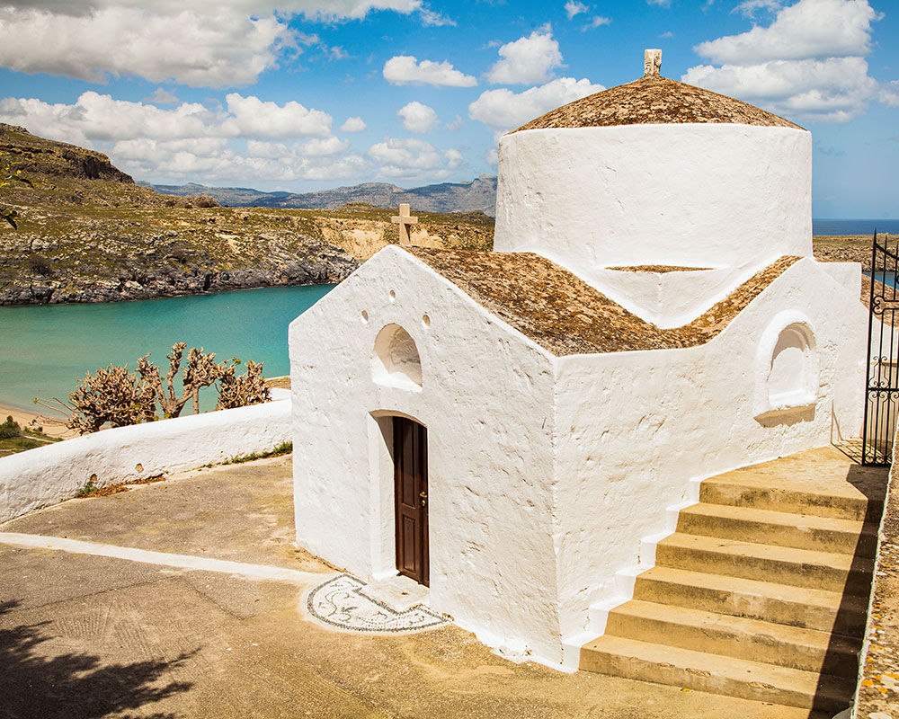 Eine kleine weiße Kirche mit Stufen, die zu einem Sandstrand hinunterführen