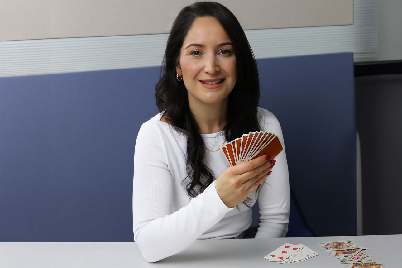 Vier Personen sitzen am Tisch und spielen Karten. Sie konzentrieren sich auf ihre nächsten strategischen Spielzüge.