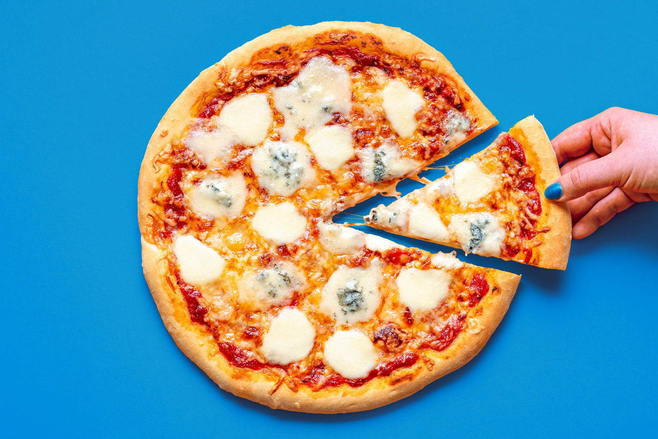 Eine Hand nimmt ein Stück von einer Pizza
