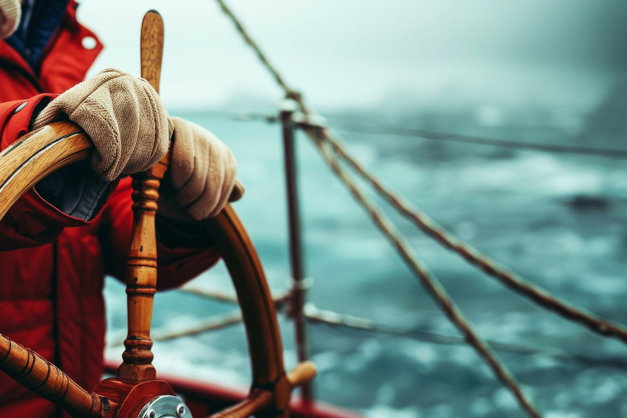 eine Person am Steuer eines Schiffes eine Person am Steuer eines Schiffes