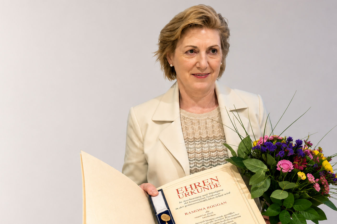 Frau Roggan mit offener Ehrenurkunde und Blumenstrauß.
