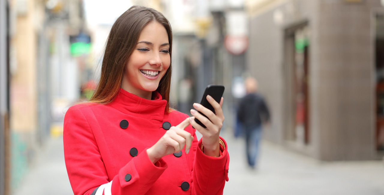Frau mit Einkaufstasche nutzt Online-Banking unterwegs