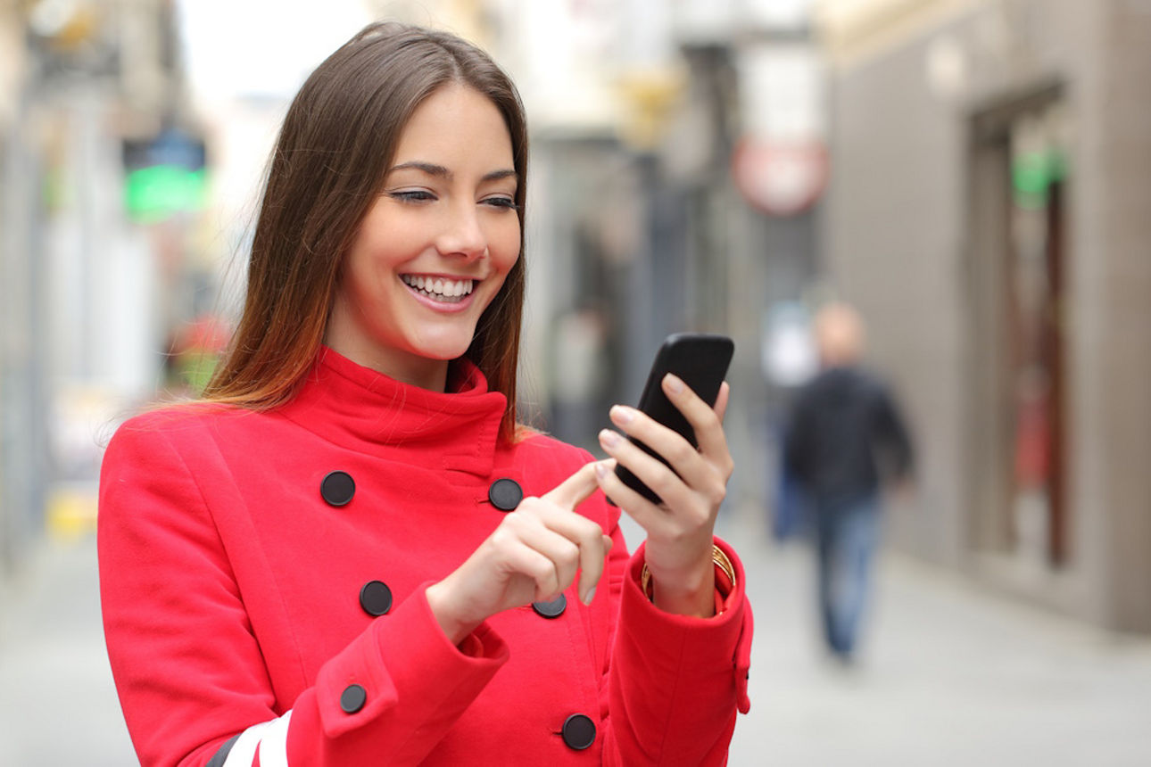 Frau mit Einkaufstasche nutzt Online-Banking unterwegs