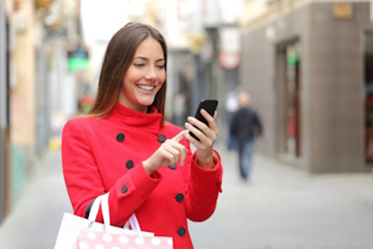Frau mit Einkaufstasche nutzt Online-Banking unterwegs