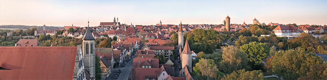 Stadtansicht mit historischen Türmen, Bäumen und Häusern bei Sonnenlicht, Text: „Gemeinsam stark für unsere Region“.