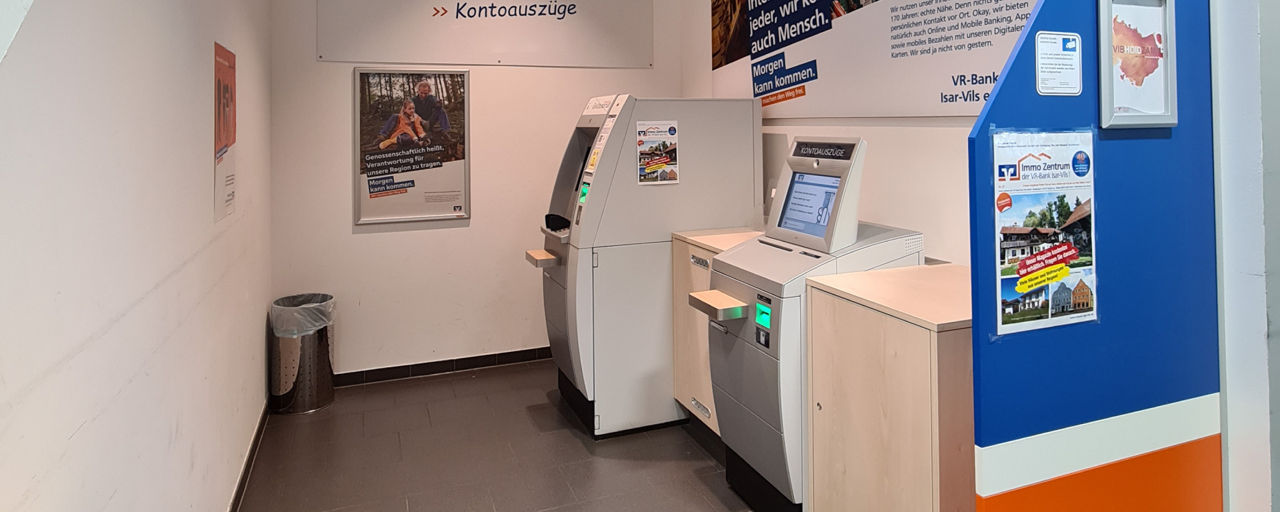 Zwei SB-Geräte nebeneinander. Im Hintergrund sind Plakate über Kreditkarten aufgehängt.