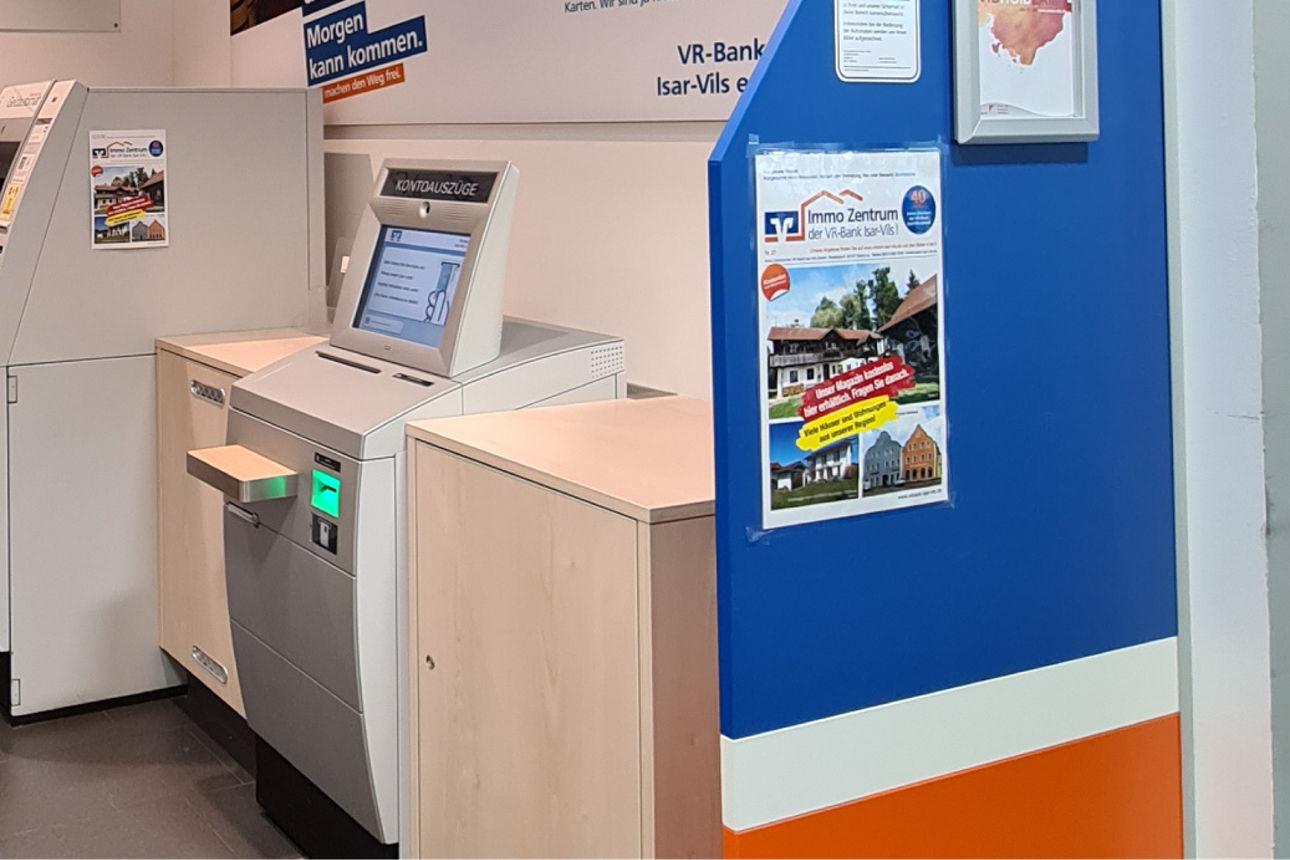 Zwei SB-Geräte nebeneinander. Im Hintergrund sind Plakate über Kreditkarten aufgehängt.