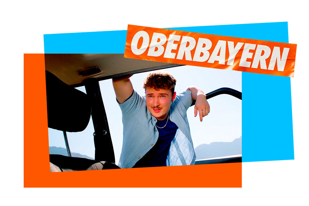 Ein junger Mann lehnt an einer Autotür und schaut in das Auto hinein. Darüber ein Sticker mit der Aufschrift "Oberbayern".