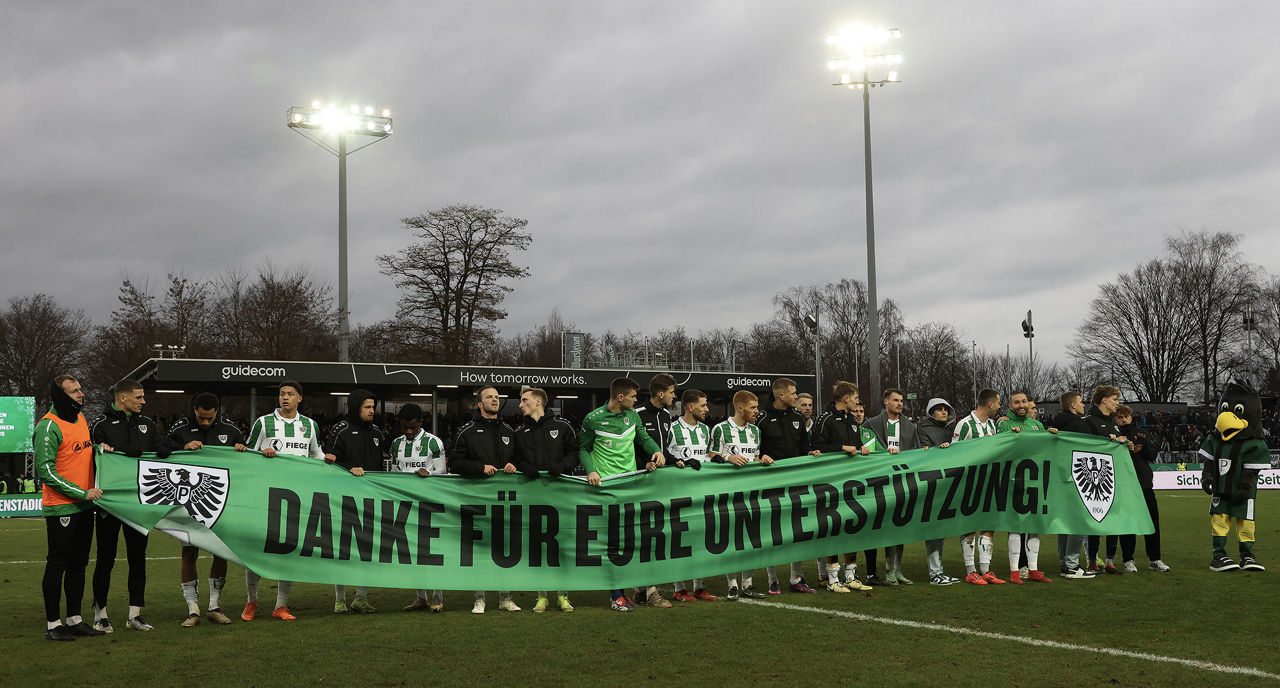 Die Mannschaft mit einem Banner auf dem "Danke für Eure Unterstüzung" steht