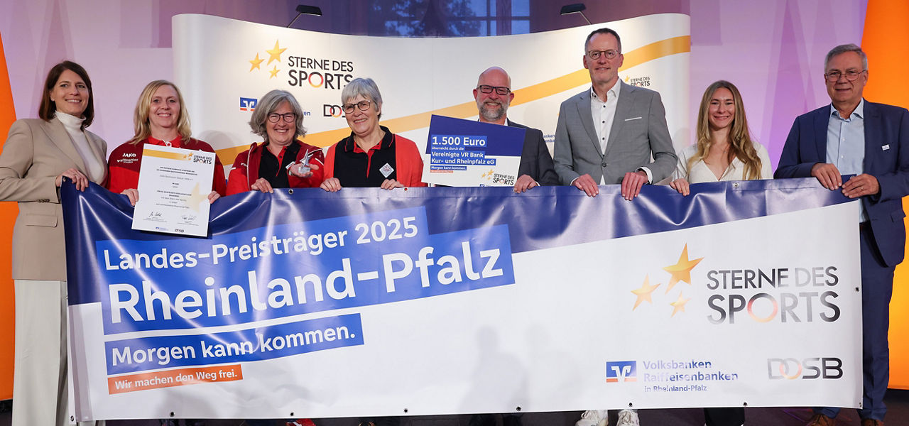Teilnehmende der Preisübergabe stehen hinter dem Banner der Aktion Sterne des Sports