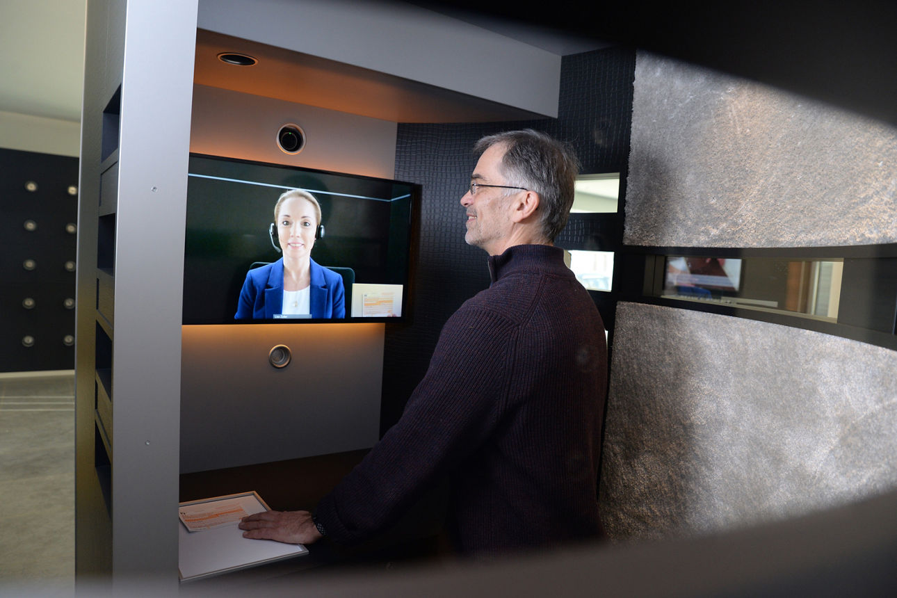 Kunde steht im VR-Service-Interaktiv-System und unterhält sich mit einer Mitarbeiterin per Videoübertragung.