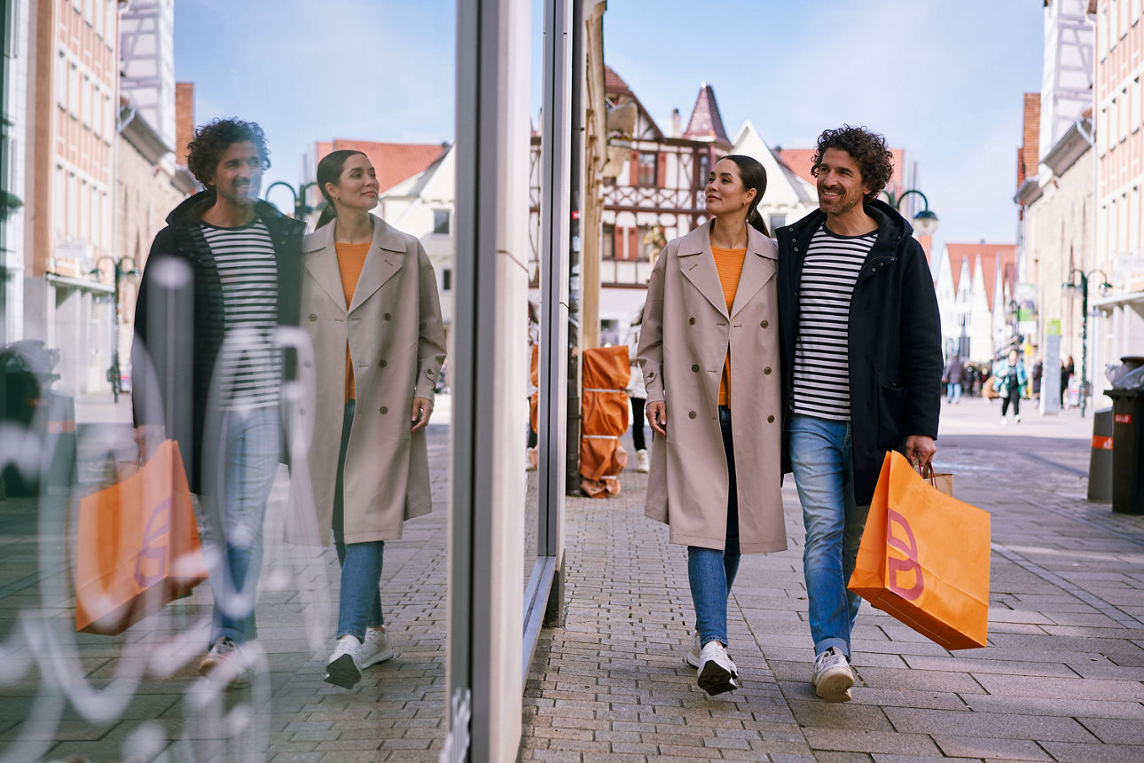 Eine Dame und ein Herr gehen an einer Fensterfront vorbei