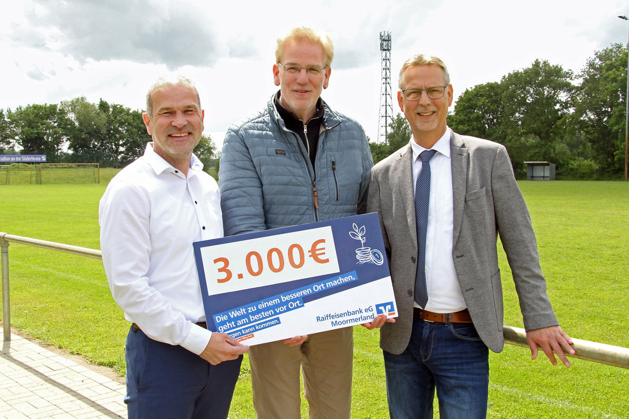 Drei Personen stehen auf dem Sportplatz 