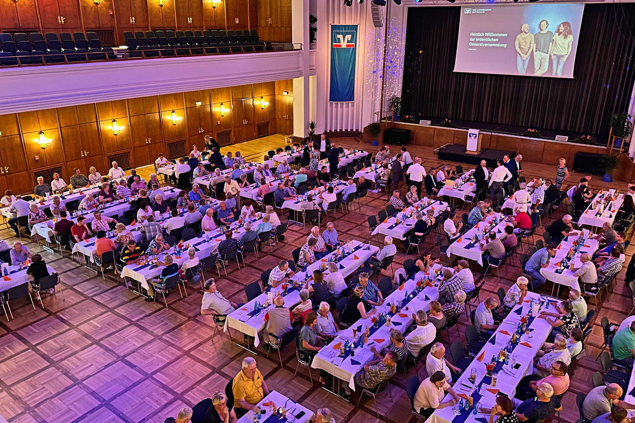 Die Mitglieder der Volks- und Raiffeisenbank Saale-Unstrut sitzen an Tischen bei der Mitgliederversammlung 2025